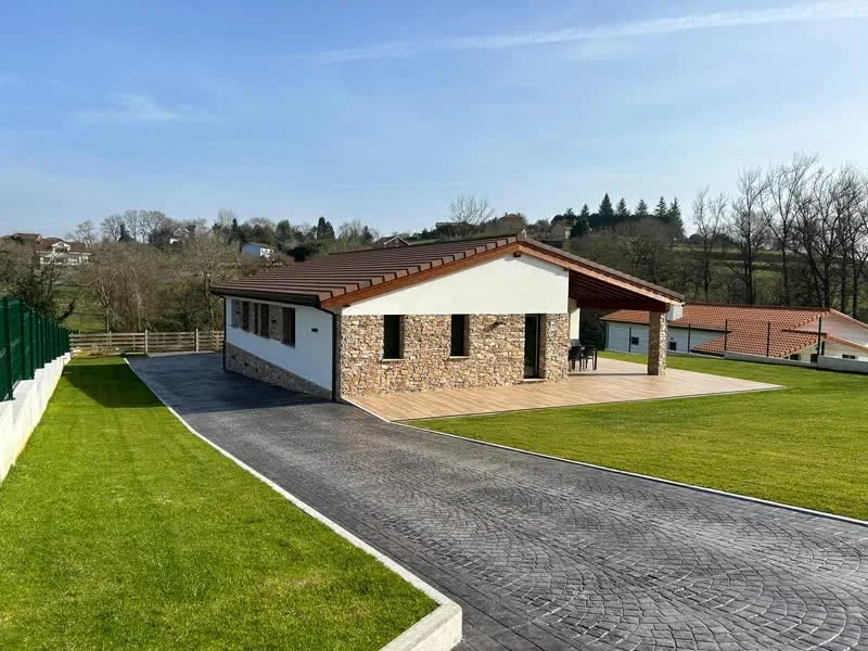 Bungalow unifamiliar con fachada de piedra, terraza de madera y jardín en Asturias
