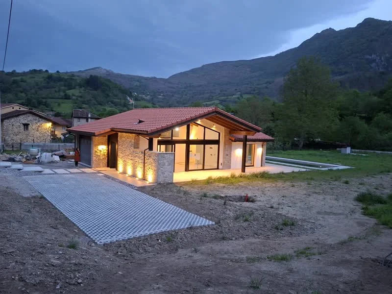 Vivienda unifamiliar iluminada al atardecer con montaña de fondo en Asturias
