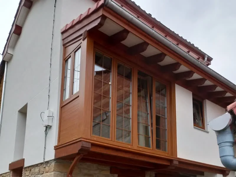Rehabilitación de vivienda asturiana con galería de madera y fachada de piedra